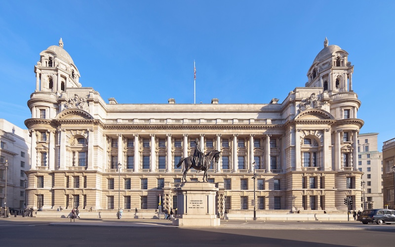 Wide view of the Old War Office, an elaborate stone building, under a blue sky